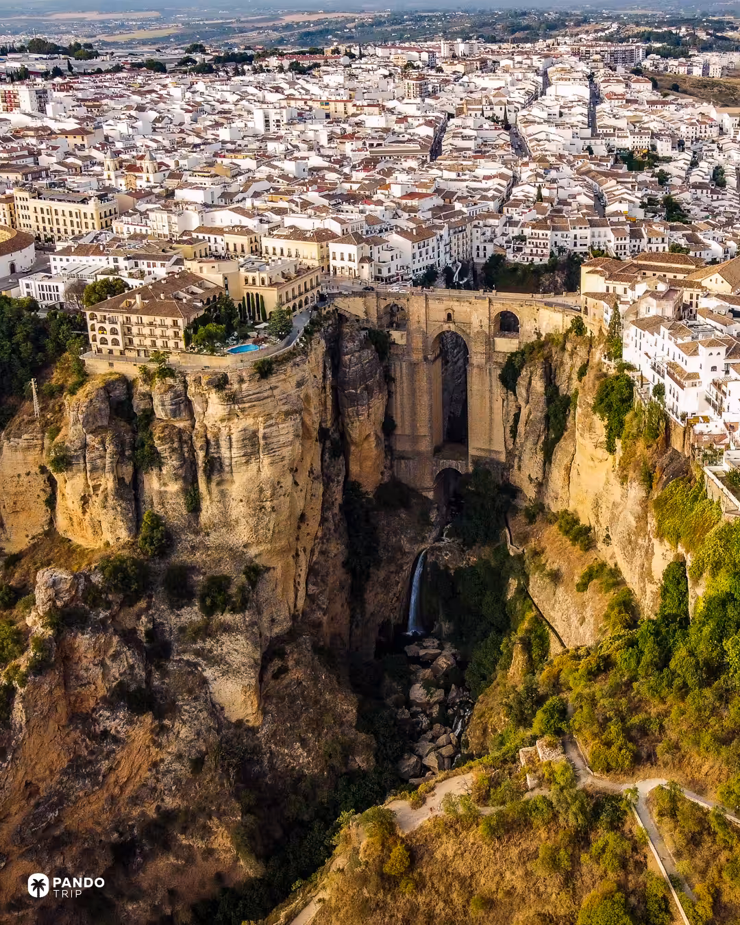 Aerial view of Ronda's whitewashed town spreading behind the Puente Nuevo and the cliffs of the El Tajo gorge.