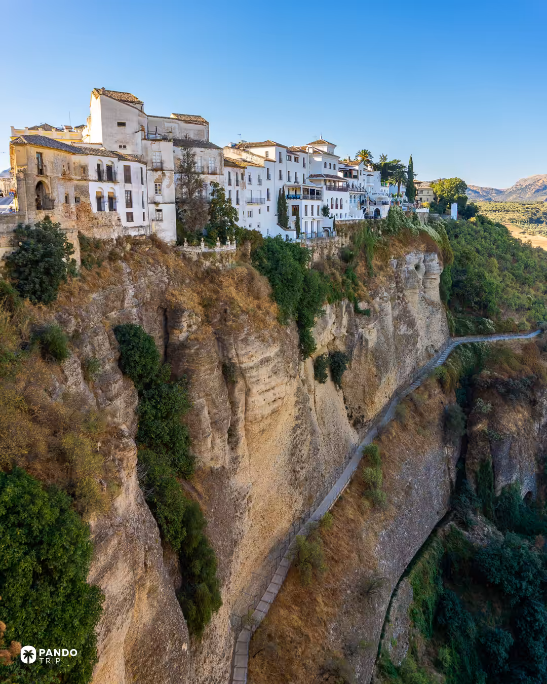 Whitewashed houses standing right on the edge of a tall rock cliff in Ronda, Spain.