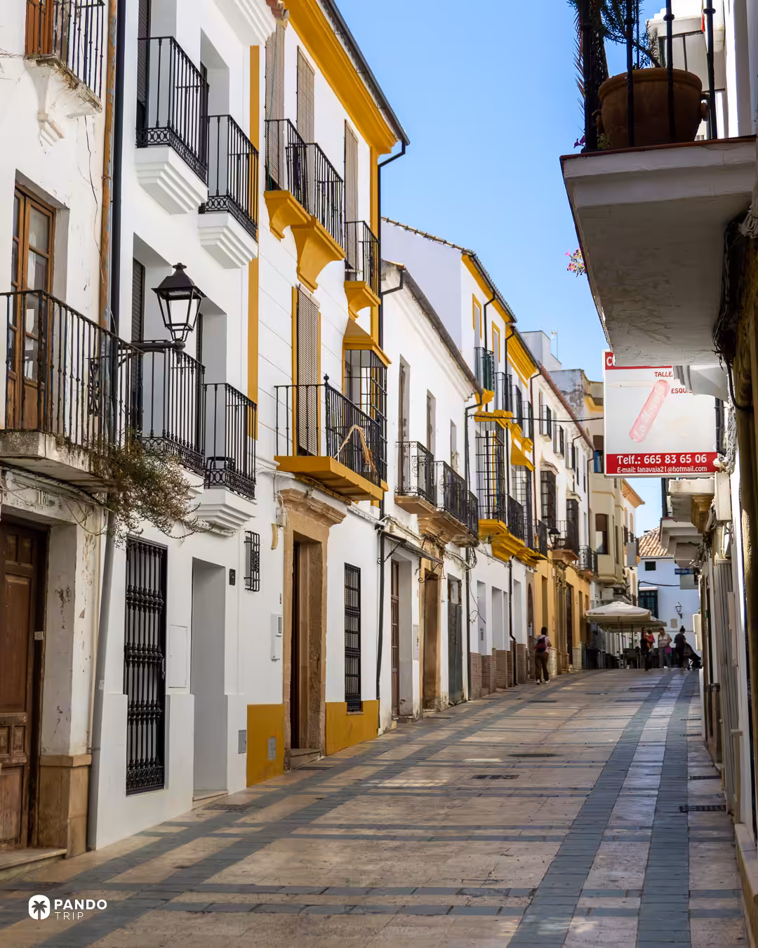 A long Ronda street of white houses with yellow trim and iron balconies.