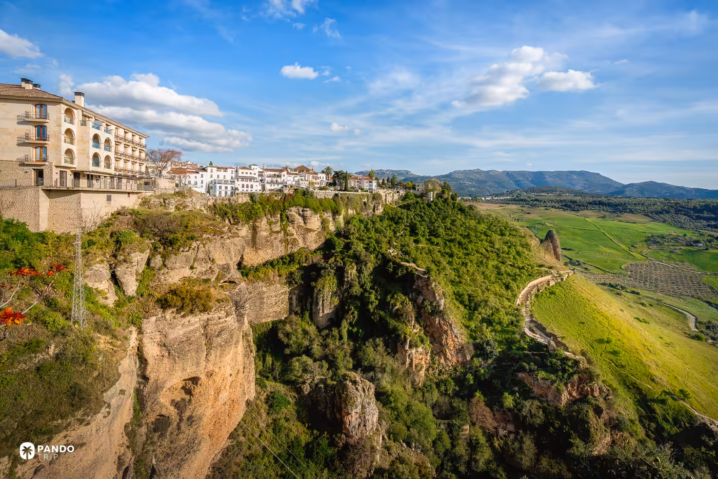 The cliffs at the edge of Ronda dropping to green countryside, with the town on top.